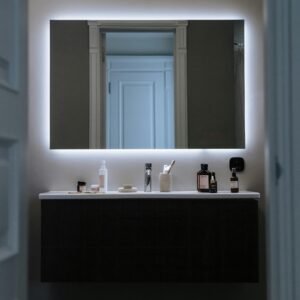 Contemporary bathroom featuring a sleek design with LED mirror and cosmetic products.