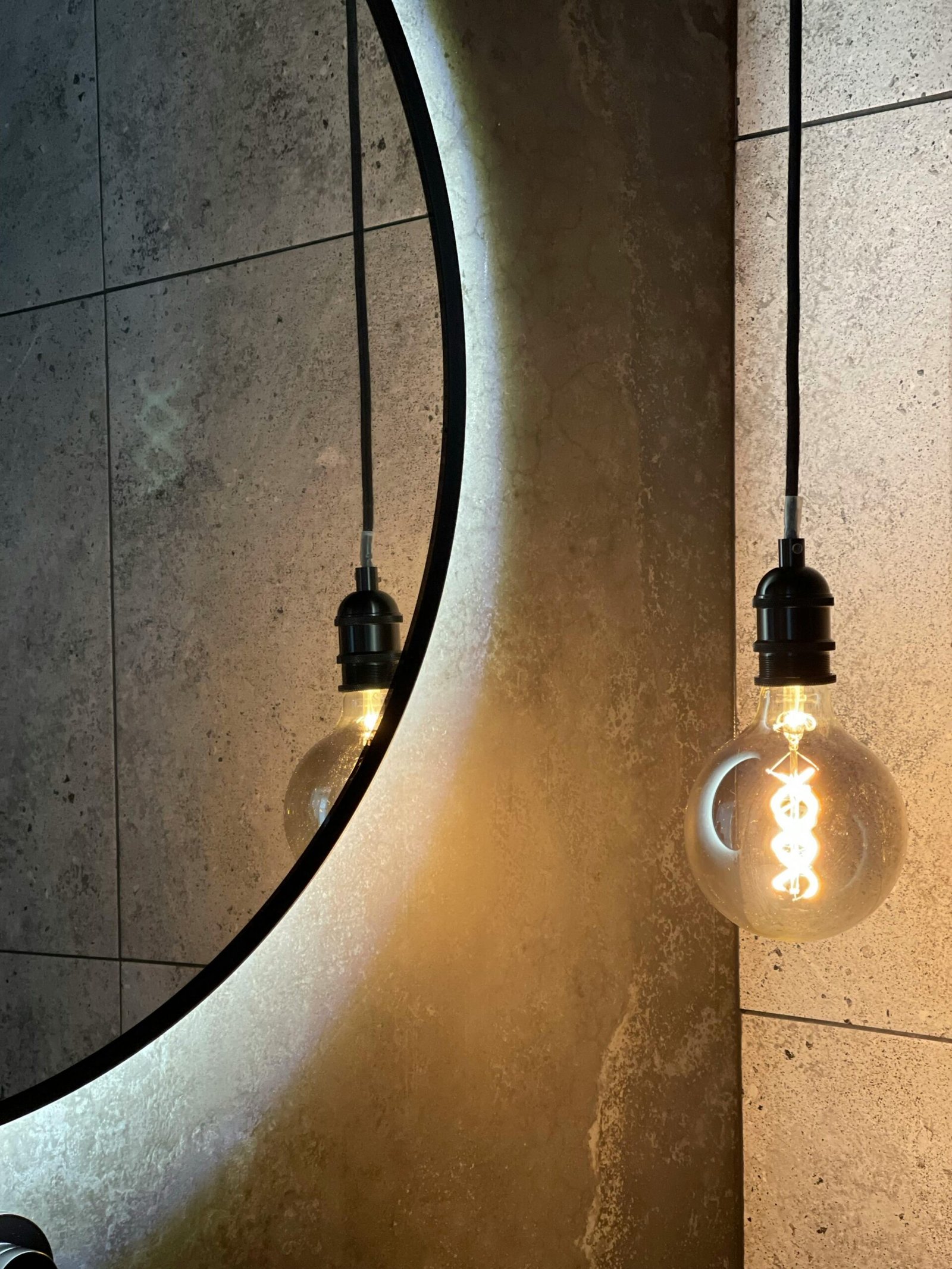Modern bathroom design featuring a backlit mirror and filament light bulb.