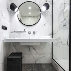 Elegant bathroom with marble walls, round mirror, and contemporary lighting.